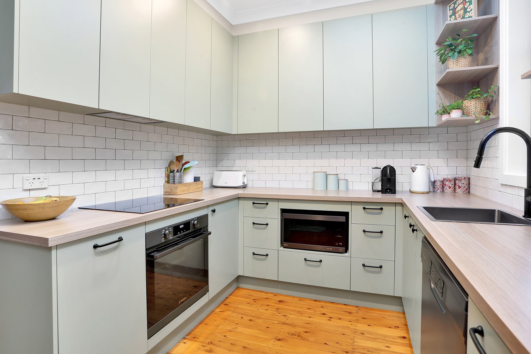 Compact sage-green kitchen with a timber benchtop — illustrative image